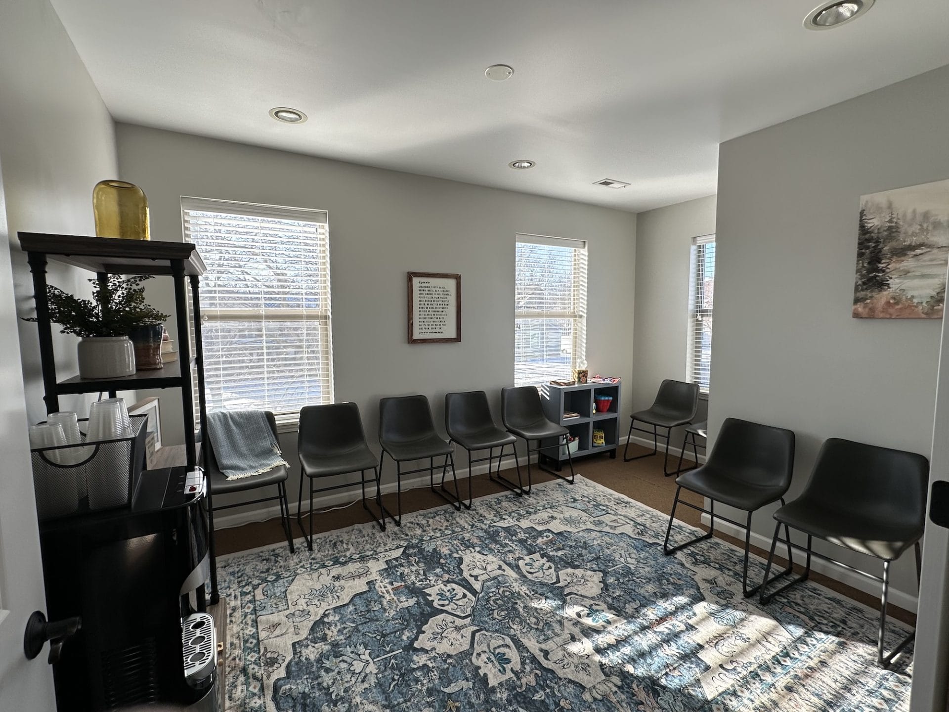 Welcoming waiting room with chairs lining the walls, a refreshment station, calming artwork designed for clients to wait for appointments