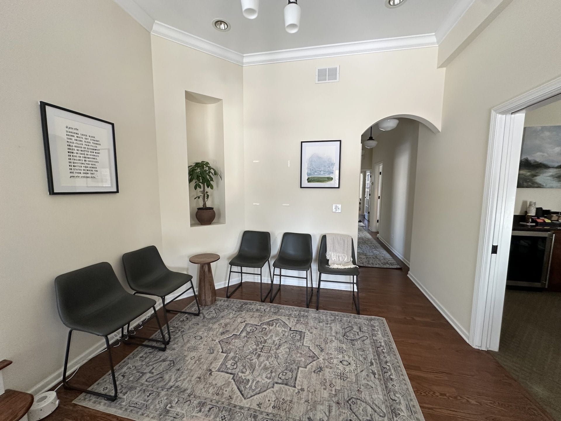 Waiting space at Wellspring Center for Counseling in a room with neutral paint, arched doorways and calming artwork and decor