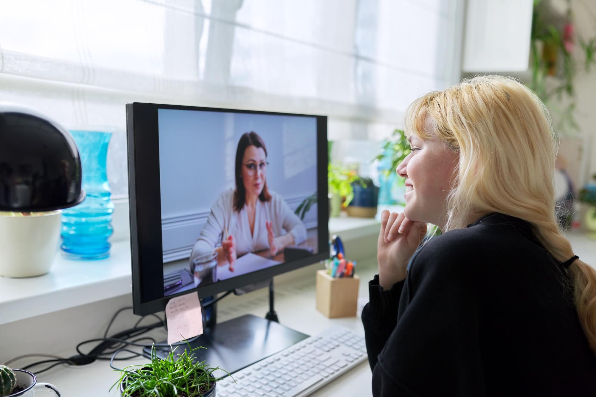 Woman participating in an online telehealth counseling session from home while speaking with a therapist on a computer video call.